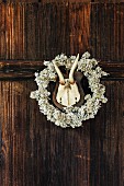 Jagdtrophäe mit Rehgeweih an einer Holzwand mit Blütenkranz