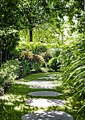 Gartenweg aus eingewachsenen Trittplatten im halbschattigen Garten