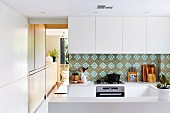 Splash guard with patterned wall tiles in a white, open kitchen