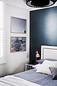 Bett mit Kissen und weißem Kopfteil vor schwarzer Wand im Schlafzimmer