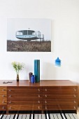Vases on retro sideboard, blue pendant lamp and photo with architectural motif