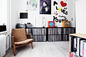 Worn retro armchair in front of record collection in black shelving modules in living area