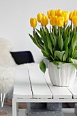 Bouquet of yellow tulips on white wooden coffee table