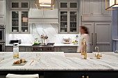 Woman walking through luxurious kitchen with marble worksurfaces