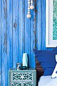Bedside table next to bed in front of a blue partition