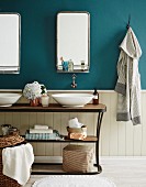 Vintage washstand with two white wash bowls, mirror with shelf on petrol blue wall