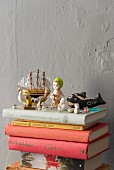 Retro toys and miniature figurines on stacked books against grey wall