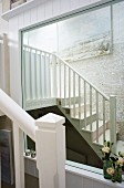 Reflection of staircase in wall-mounted mirror with white wooden frame