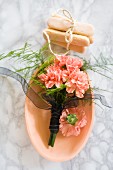 Bouquet of carnations in ceramic bowl and sponge fingers tied with string on marble surface