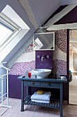 Wooden roof beams in lilac and violet attic bathroom
