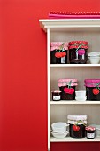 Hand-sewn cherry tags for jars of jam on white open-fronted shelves