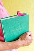 Hand holding book with pink origami bookmark