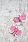 Pink and white, hand-made felt butterflies wrapped with copper wire on vintage wooden surface