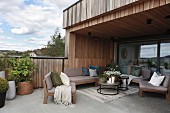 Roofed terrace with concrete floor adjoining wood-clad house