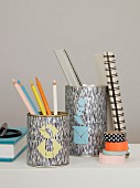 Writing utensils in metal tins decorated with coloured tangram triangles