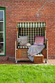 Scatter cushions and blanket in traditional beach chair against brick wall