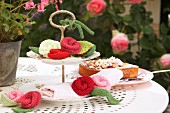 Cake stand decorated with various knitted flowers on white metal table