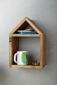 Books, cup and glasses on hand-made, wooden, house-shaped shelf