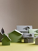 Green and grey cardboard models of houses on yellow surface