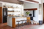 Counter and bar stools in open-plan kitchen with terracotta floor tiles