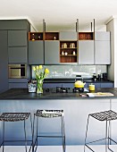 Elegant blue and grey fitted kitchen with counter and bar stools