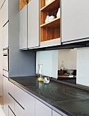 Elegant blue and grey fitted kitchen with serving hatch made from sliding glass panels