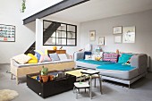 Colourful scatter cushions on sofa and black stairs leading to mezzanine