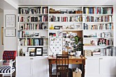 Vintage desk and wooden chair surrounded by white bookcase