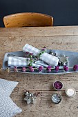 Branch of purple beautyberry and checked linen napkins with rosemary napkin rings on wooden table