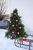 Christmas tree decorated with candles and home-made gingerbread shapes in snow
