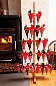 DIY-Adventskalender mit Holzständer und nummertierten Spitztüten neben gemütlichem Kaminfeuer