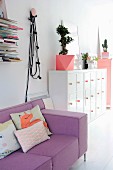 Scatter cushions on lilac couch next to Bonsai tree on top of white retro cabinet