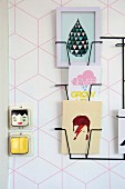 Delicate black magazine rack on wall with geometric, pink-patterned wallpaper