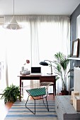 Retro desk, classic chair and houseplants in front of window