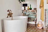 Moderne, freistehende Badewanne mit nostalgischer Armatur vor Retro Glasvitrine