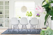 White shell chairs around dining table in front of window
