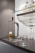 A glass of beer under a tap in a kitchen