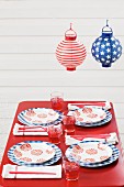 Outdoor table set for Fourth of July below paper lanterns (USA)