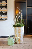 Floor vase decorated with floral pattern next to watering can