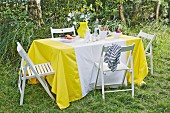 A homemade yellow and white tablecloth on a summery table outdoors
