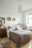 Gemütliches Schlafzimmer mit antikem Nachtkästchen und Wandtellern