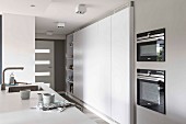 Ausschnitt einer Küchentheke, gegenüber moderner Einbauküchenschrank in Weiß in offener Küche