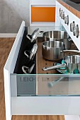 An open drawer of pots and lids with a lid insert