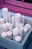 Lit white candles in blue-painted wooden crate