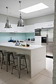 Island counter, dining area and bar stools in white modern kitchen