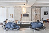 Lounge mit fahrbaren Paletten-Sitzsäcken in Loftwohnung mit Ziegelwand und Betonboden