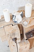 White candles and stone on rustic wooden sculpture