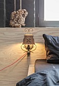 Vintage-style sconce lamp on wood-grained headboard and black bed linen