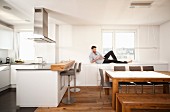 Mann mit Smartphone liegt auf den Schränken in der Küche