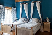 Twin beds with white bed crowns on blue wall in bedroom